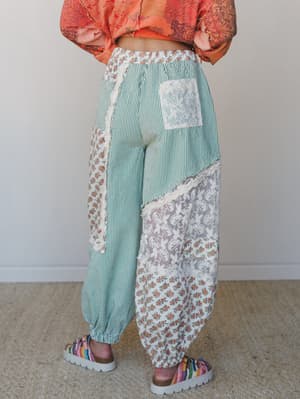 A back-view shot of wide-leg patchwork pants in mint stripe, floral print, and lace panels — the kind of pants that look like they were made from your grandmother's favorite quilts, in the best possible way.