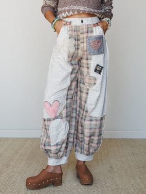 Patchwork balloon pants covered in heart appliqués and mixed fabric panels — plaid, ditsy floral, lace, and embroidery all living their best life together — styled with a cropped fair isle sweater and wooden clogs.