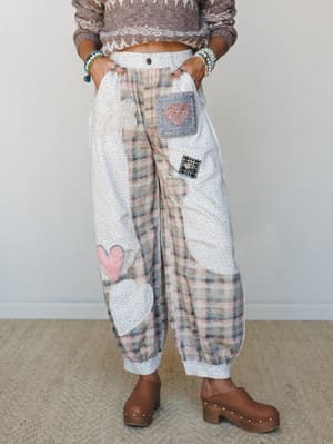Patchwork balloon pants in soft plaid and ditsy floral fabrics, covered in heart and flower appliqués — styled with a cropped fair isle sweater and wooden clogs for a cozy, handmade-feeling outfit that looks like your grandma's quilt decided to becom