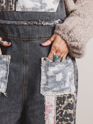 Close-up of a person wearing patchwork overalls with various patterns and textures.