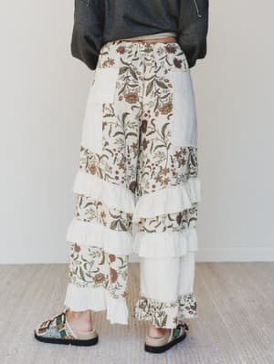 Person wearing floral tiered pants with a plain background