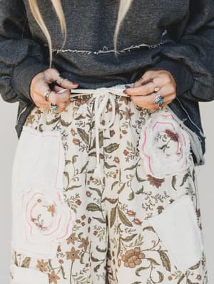 Person wearing floral pants with a plain background
