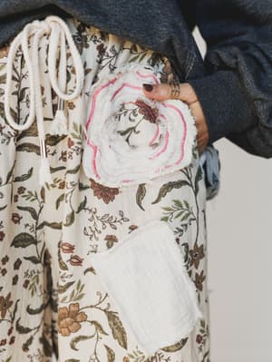 Person holding a white towel with floral patterns against a neutral background