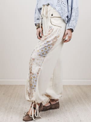 Person wearing a light-colored outfit with floral patterns on a neutral background