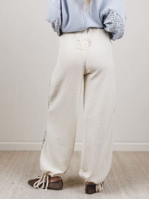 Person wearing light-colored pants and a blue shirt with a white background