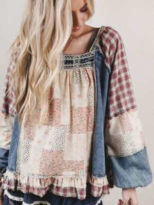 Woman wearing a patchwork dress with plaid sleeves and denim accents.