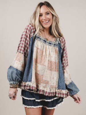 Woman wearing a plaid shirt over a patterned dress with denim accents on a plain background