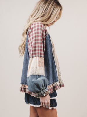 Woman wearing a patchwork denim jacket with a plaid shirt underneath on a plain background