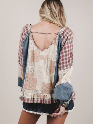 Back view of a person wearing a patchwork blouse with plaid sleeves on a plain background