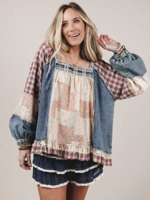 Woman wearing a patchwork dress with denim accents on a plain background