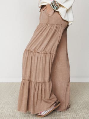 Tiered wide-leg pants in a soft mocha mineral wash, styled with a cream oversized top, stacked beaded bracelets, and floral sandals — the kind of outfit that looks effortless but clearly wasn't an accident.