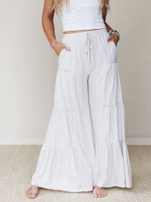 Flowy tiered wide-leg pants in a soft natural white paired with a white crochet crop top — the kind of effortless outfit that looks equally at home on a beach boardwalk or a slow Sunday morning.
