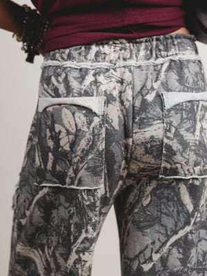 Camouflage pants with a person wearing a red top, on a plain background