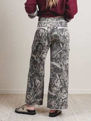 Person wearing camouflage pants with a plain background
