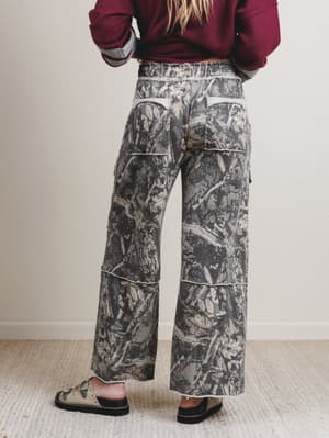 Person wearing camouflage pants with a plain background