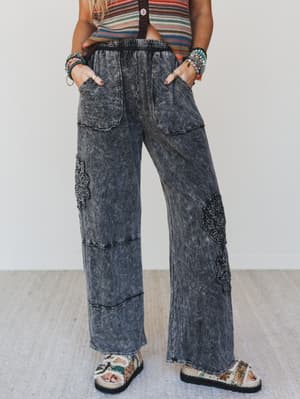 Person wearing acid-wash jeans and a colorful top on a light background