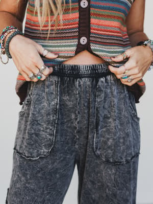 Person wearing a striped sweater and acid-wash jeans with visible jewelry.