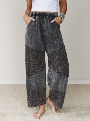 Acid-washed wide-leg pants in a muted ash black leopard print, styled with a white lace crop top and stacked boho bracelets — the kind of pants that do all the talking so you don't have to.