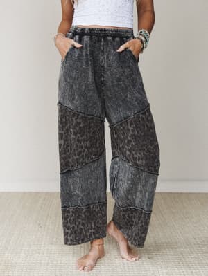 Acid-washed wide-leg pants in a muted ash black leopard print, styled with a white lace crop top and stacked boho bracelets — the kind of pants that do all the talking so you don't have to.