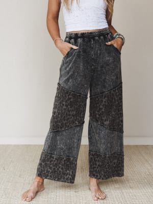 Wide-leg pants in an acid-washed ash black with a faded leopard print throughout, styled with a white eyelet crop top and turquoise stacked bracelets — the kind of outfit that looks effortless but definitely wasn't an accident.
