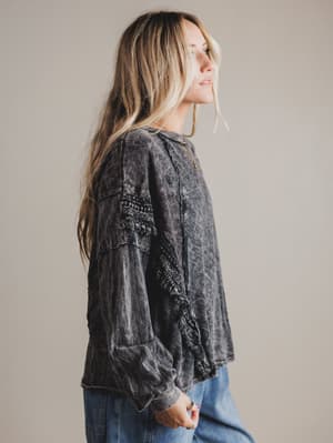 Woman wearing a dark acid-wash denim top against a plain background