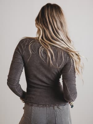 Person wearing a brown ribbed sweater with a neutral background
