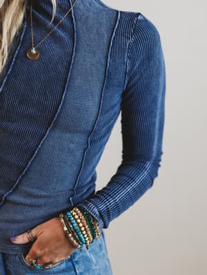 Person wearing a blue ribbed sweater with a neutral background