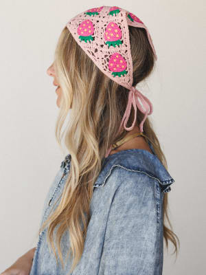 A sun-warmed side profile shot of a model wearing a crochet granny square headscarf covered in strawberry motifs — tied at the nape and layered over a denim shirt, the whole thing feels like summer at a farm stand.
