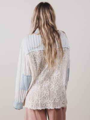 Person wearing a light blue lace top with a plain background