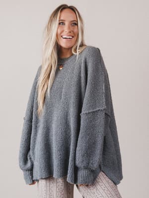 Woman wearing a gray sweater against a plain background