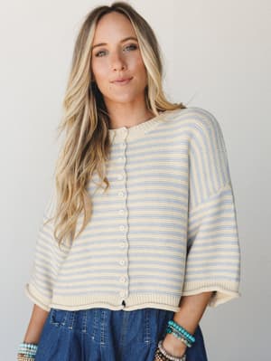 A breezy striped knit cardigan in cream and soft periwinkle worn over a denim skirt — the kind of sweater that feels like a good afternoon with nowhere to be.