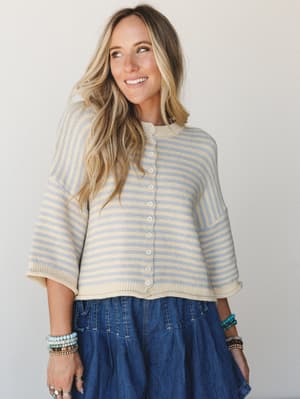 A striped button-front cropped knit sweater in cream, soft blue, and yellow paired with a denim tiered skirt — the kind of effortless, lived-in combo that looks like it came together without trying.