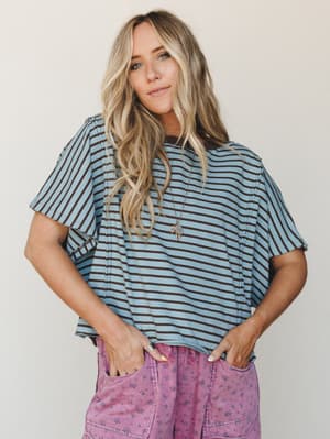 A relaxed striped tee in dusty blue and brown paired with faded floral pants — the kind of effortless mix that looks like it came together without trying but definitely didn't.