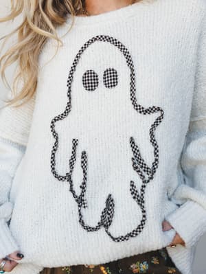 A cozy ivory knit sweater with a charming gingham-appliqué ghost graphic — the kind of Halloween piece you'd actually want to wear all of October, not just on the 31st.