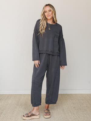 A matching washed charcoal sweat set — cropped pullover and relaxed joggers — styled with leopard print platform sandals and layered gold jewelry for that effortless 'I put this together in two minutes and it works' energy.