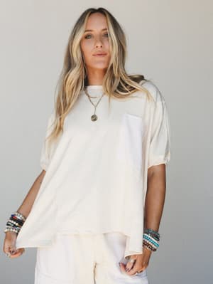 An oversized cream tee styled with matching wide-leg pants and stacked beaded bracelets — the kind of effortless monochromatic moment that looks like you tried just the right amount.