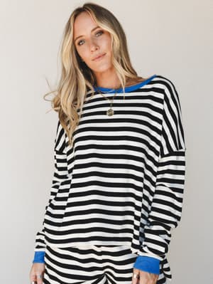 A relaxed oversized striped long-sleeve top with cobalt blue contrast trim at the collar and cuffs, styled with layered gold necklaces — the kind of effortless set you reach for on repeat.