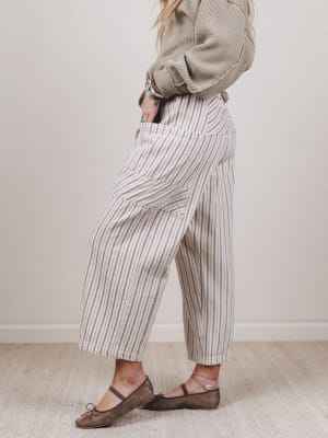 Person wearing striped pants and a patterned sweater against a plain background