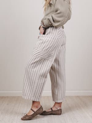 Person wearing striped pants and a patterned sweater against a plain background