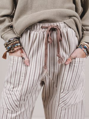 Person wearing striped pants with a neutral background