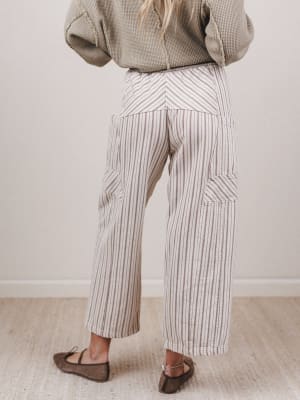 Person wearing a green sweater and striped pants against a white wall.