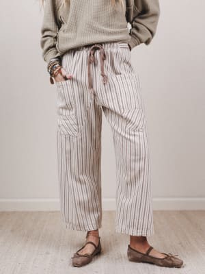 Person wearing striped pants and a beige sweater in a minimal indoor setting