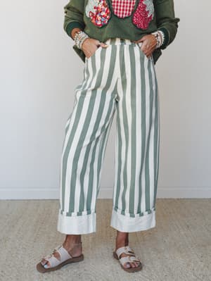 Wide-leg striped pants in sage and cream take center stage, styled with an embellished green sweatshirt and buckle sandals — a playful, put-together look that feels effortless without trying.