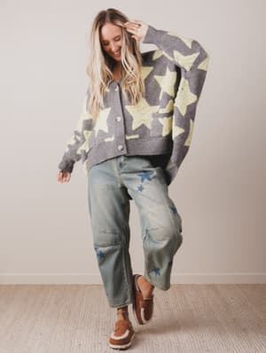 Woman wearing a star-patterned cardigan and jeans indoors.