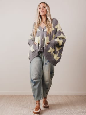 Woman wearing a star-patterned cardigan and jeans indoors.