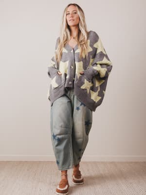 Woman wearing a star-patterned cardigan and jeans indoors.