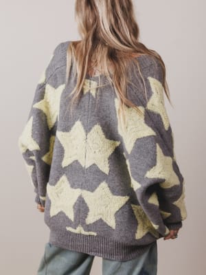 Person wearing a gray sweater with large yellow stars on a plain background