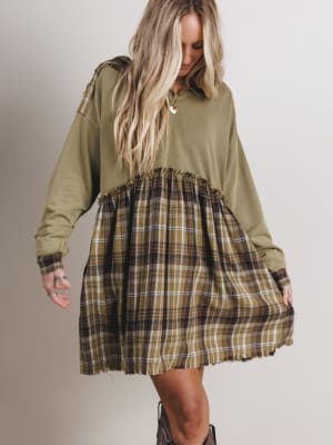 Woman wearing a green dress with plaid skirt on a plain background