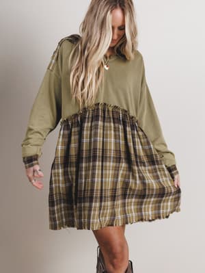 Woman wearing a green dress with plaid skirt on a plain background