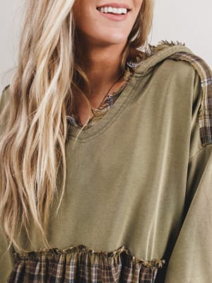 Person wearing a green oversized shirt with plaid accents